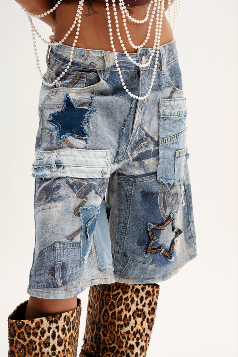 Wearing the STARS IN THE SKY DENIM SHORT featuring embroidered star accents, cargo pockets, and hanging metal rings. They complement this look with a pearl necklace draped from their waist and leopard print boots.