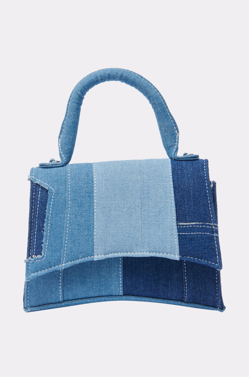 The WESTIE PATCHWORK DENIM PURSE features a structured rectangular design in assorted blue denim shades, visible seams, a top handle, and a detachable shoulder strap for versatile carry options. 1
