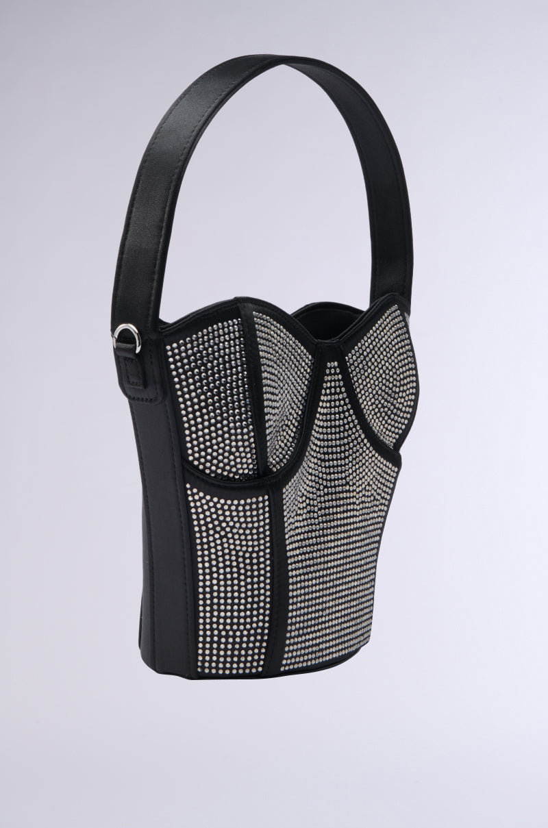 The HOLD MY BUSTIER PURSE is a black corset-shaped purse with a single strap, featuring a grid pattern adorned with small silver studs and dazzling rhinestone embellishments that mimic detailed corset stitching.