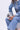 Wearing a light blue denim jacket and jeans, a person sits holding the LOVE MY VIBE HAMMERED CHROME PURSE, showcasing its textured hammered finish and stylish crossbody fit. Only their torso and legs are visible.