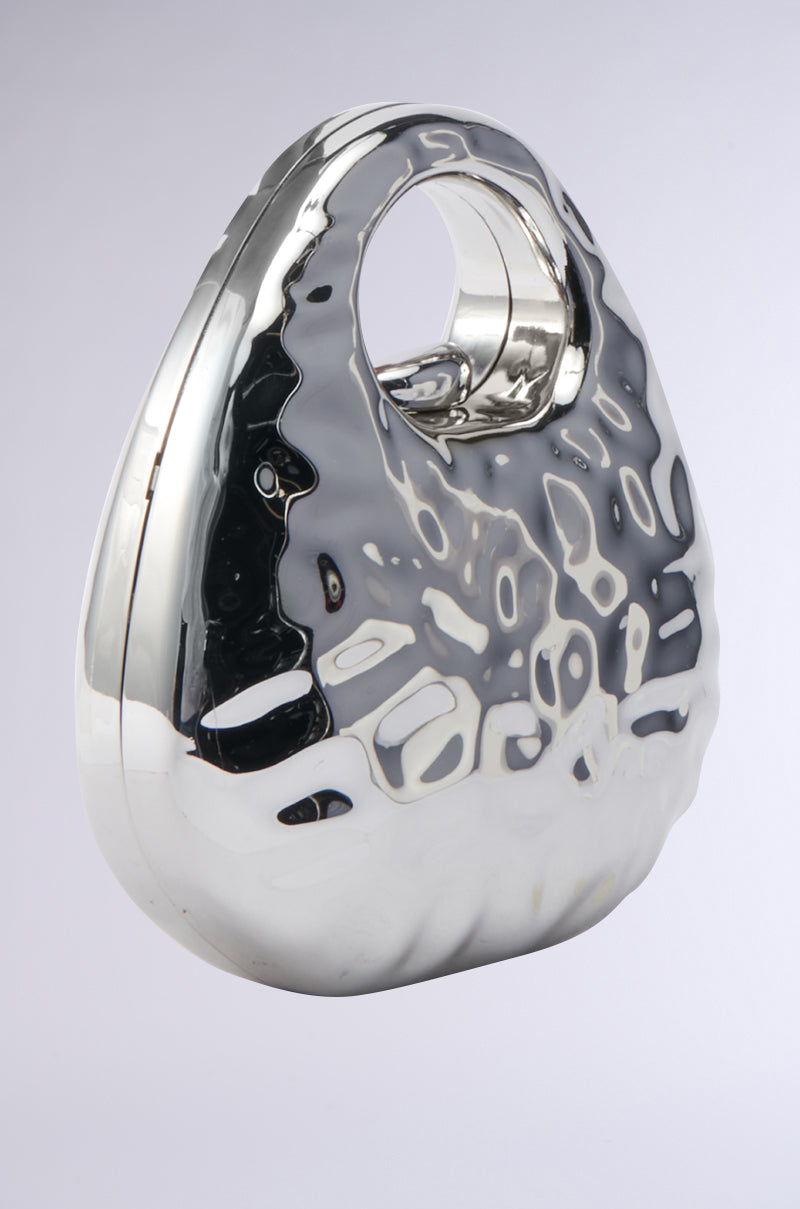 The LOVE MY VIBE HAMMERED CHROME PURSE features a shiny metallic silver finish, rounded pebble-like shape, hammered texture, large circular handle, and sleek reflective surface for a chic statement look. 3