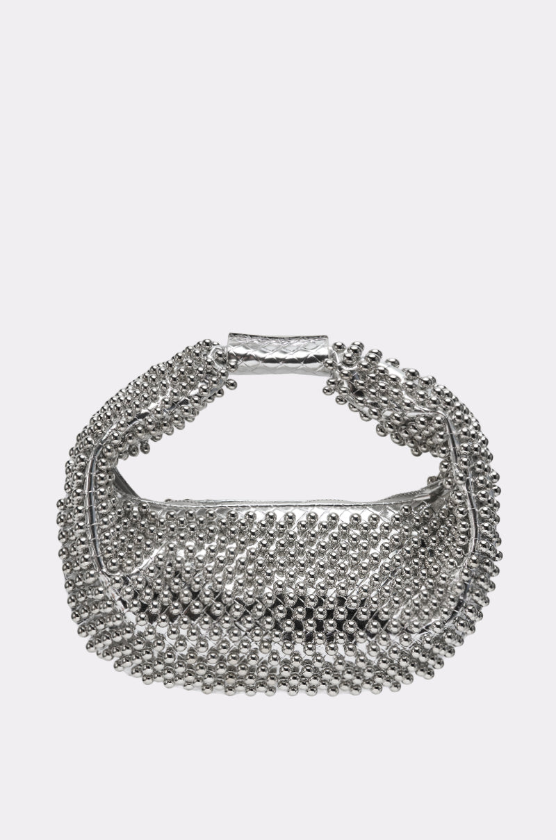 The BEADED BABE PURSE is a small, silver handbag featuring a textured surface with raised metallic studs and a short, wide handle, shown against a plain light gray background. 1