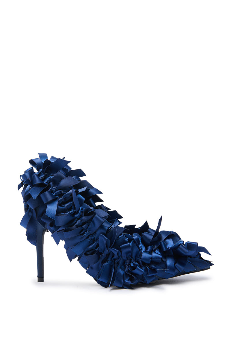 The AZALEA WANG LYLIO NAVY BOW EMBELLISHED PUMP features a navy satin pointed toe and stiletto heel, detailed with blue ribbon bows and a textured design set against a white background.