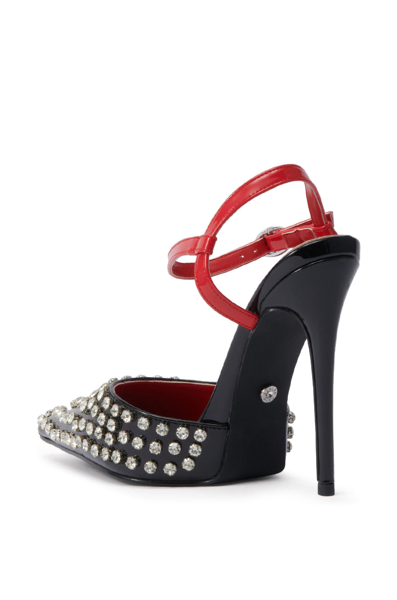 The AZALEA WANG LYSANDER BLACK MULTI PUMP STILETTO features black patent faux leather, a pointed toe, chunky gemstone embellishments, a red ankle strap, and a vibrant red inner lining.