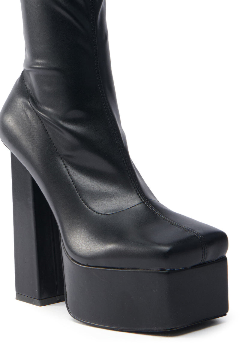 The AZALEA WANG MADDER BLACK PLATFORM BOOTIE features a sleek design with a chunky high heel, crafted from glossy faux leather that shines brilliantly, highlighting its stylish and modern appeal.