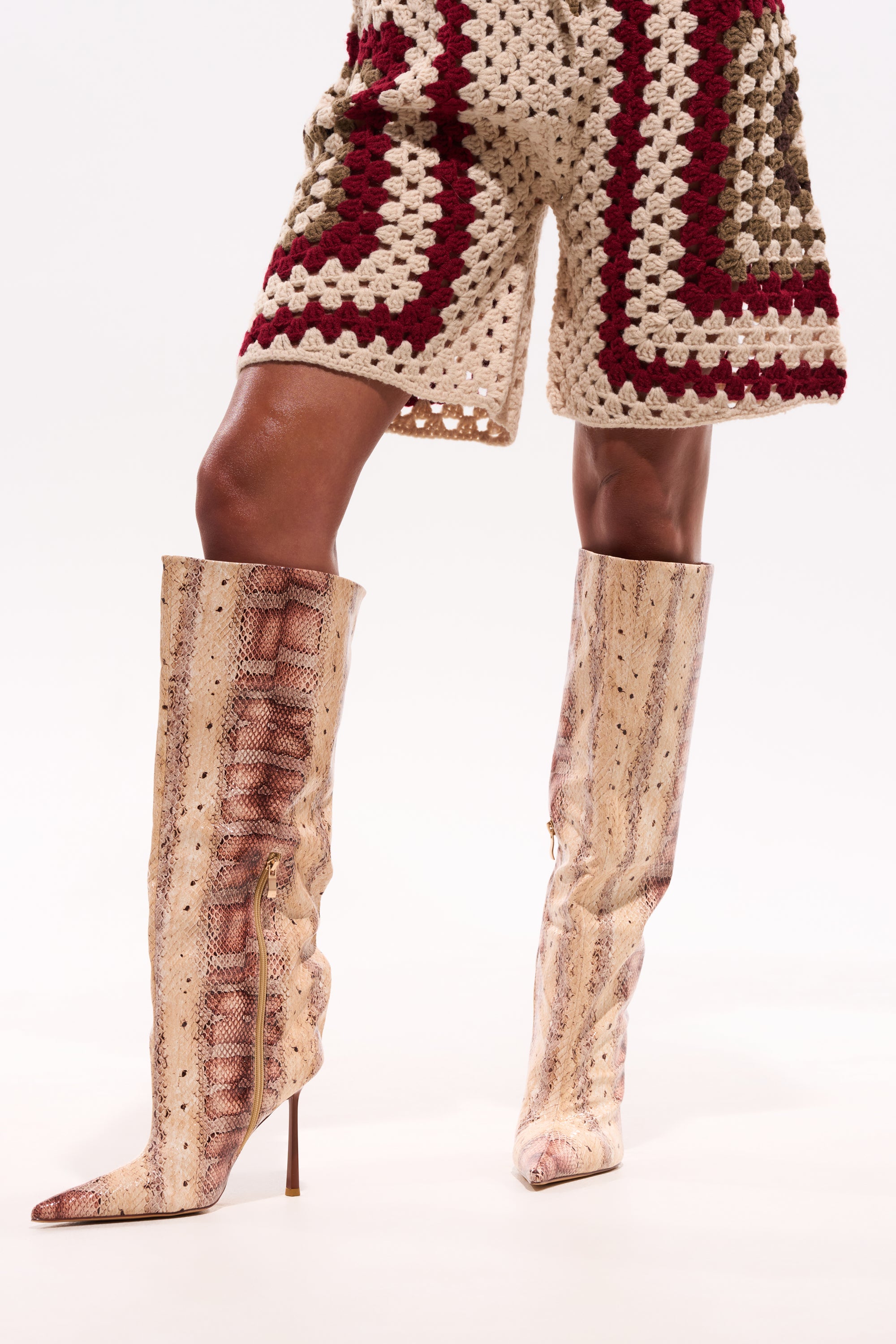 A person wearing the AZALEA WANG MADEYE NUDE SNAKE STILETTO BOOT and beige, burgundy, and olive green crochet shorts stands against a plain white background. 2