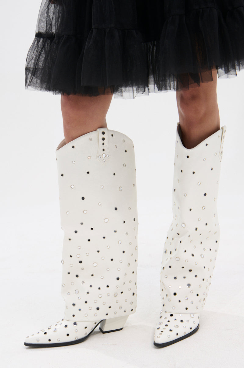 A person wearing a black tulle skirt and the AZALEA WANG MADLOCK WHITE EMBELLISHED WESTERN BOOT with metallic eyelet details stands on a white background, channeling modern rhinestone cowgirl vibes.