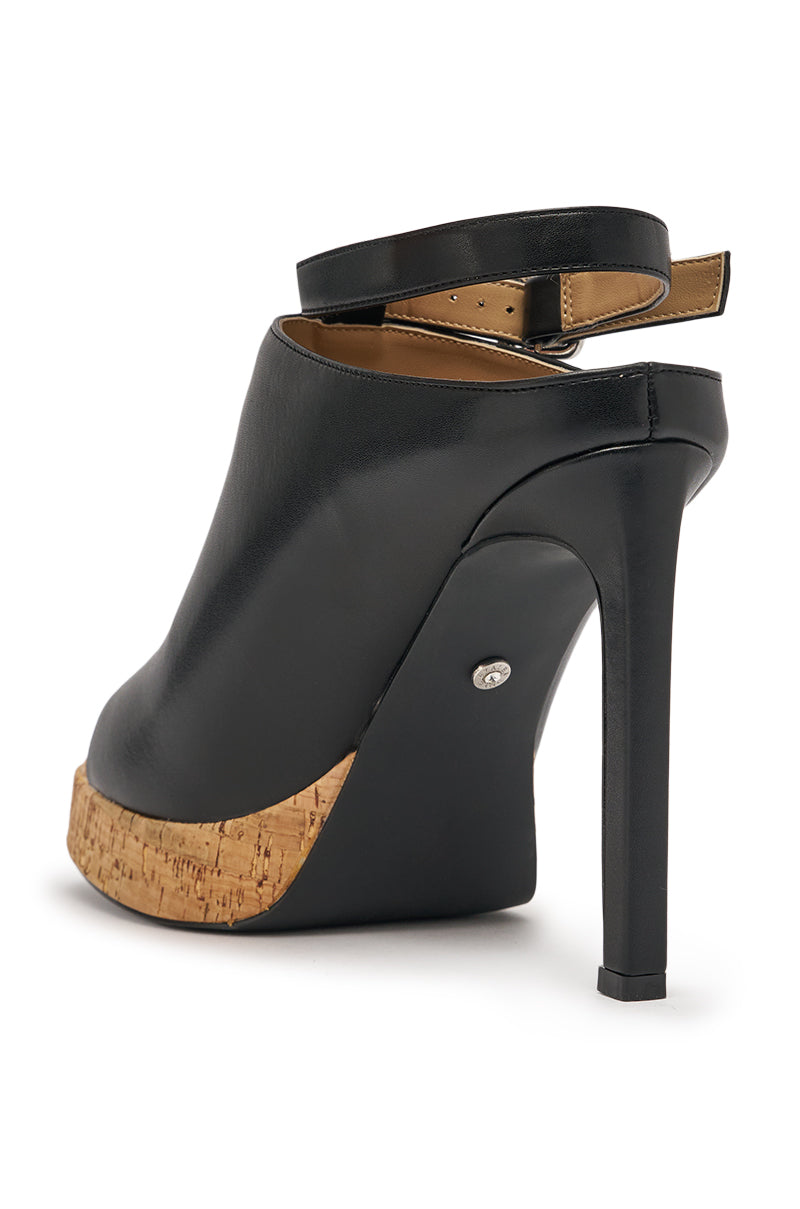The AZALEA WANG MAELIE Black and Cork Stiletto Sandal features black faux leather, a cork platform sole, closed toe, high stiletto heel, and an ankle strap, shown from the back angle against a white background. 6