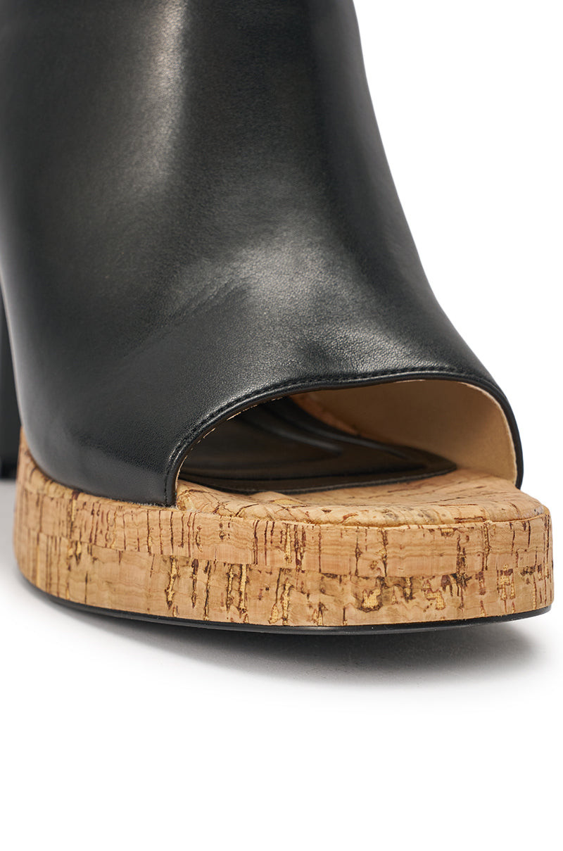 Close-up of the AZALEA WANG MAELIE Black and Cork Stiletto Sandal, featuring a black faux leather open toe and thick cork platform sole, highlighting part of the front and side. 7