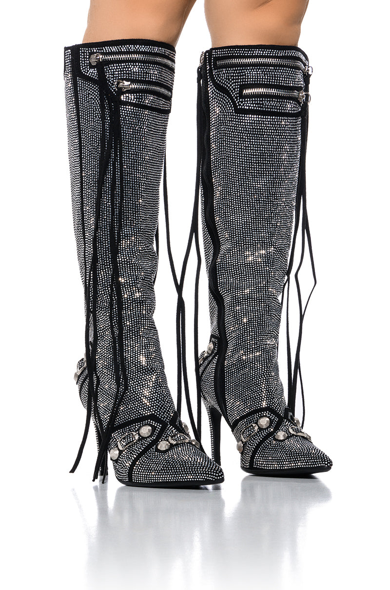 Introducing the AZALEA WANG MAEVE SILVER STILETTO BOOT: a pair of stunning knee-high boots adorned with sparkling rhinestones, featuring pointed toes and sleek stiletto heels. Black zippers, decorative black laces, and dazzling silver embellishments create a bold and glamorous look.