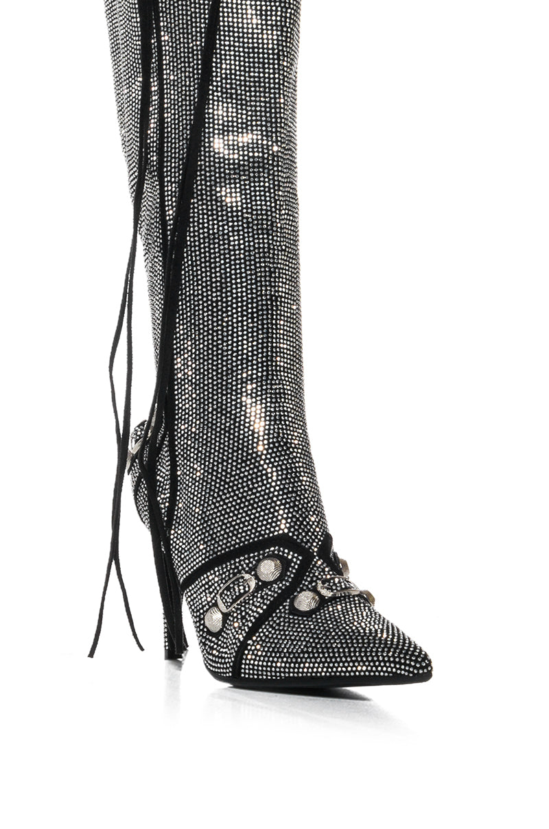 Introducing the AZALEA WANG MAEVE SILVER STILETTO BOOT: a shimmering knee-height stiletto adorned with sparkling silver details and black accents. The design boasts decorative black straps and metallic studs, enhanced by long, dangling black laces for a chic finish.