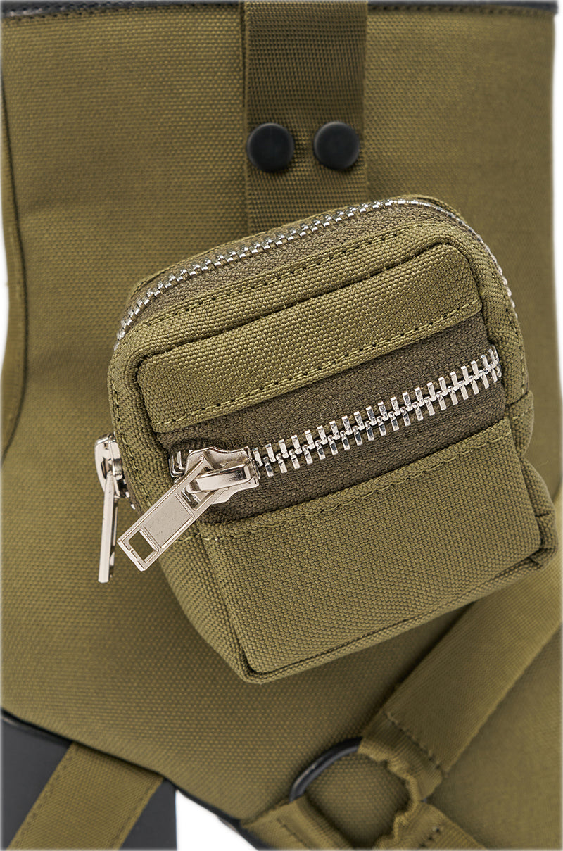 Close-up of an olive green fabric pocket with a silver zipper and small zippered pouch on the AZALEA WANG MAHOMES OLIVE SPORTY COMBAT BLOCK BOOTIE. Black hardware gives this bold street-style accessory an edgy touch. 7