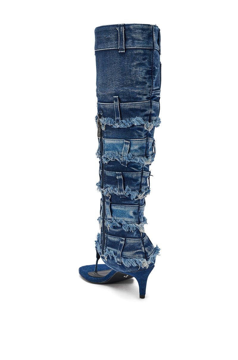 The AKIRA GOLD MAHONEY DENIM PANT DETAIL GLADIATOR STILETTO is a knee-high denim boot with frayed layers, patchwork details, visible stitching, a pointed toe, and a mid-height stiletto heel for a rugged yet stylish look. 6