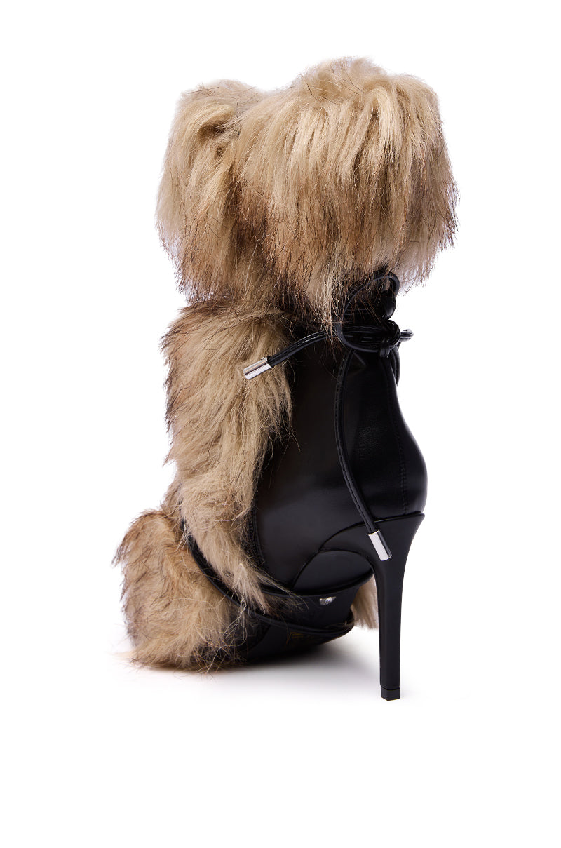 The AZALEA WANG MAHTAMA BLACK FUR EMBELLISHED BOOTIE is a high-heeled, mid-calf black boot with chunky sections of shaggy light brown faux fur and a lace-up back detail, giving it a teddy bear-inspired look.