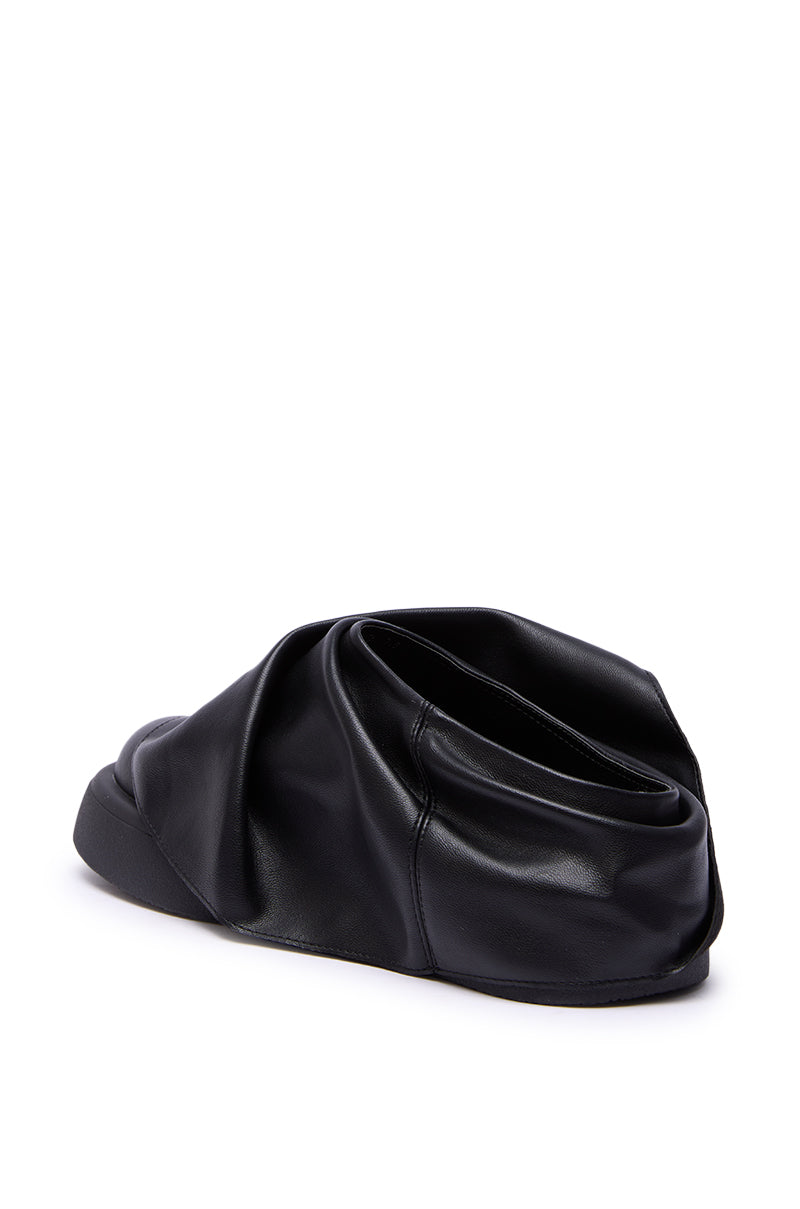 The AZALEA WANG MAITYE BLACK RUCHED FLAT is a black slip-on shoe with a scrunched faux leather design and chunky flat sole, shown on a white background.