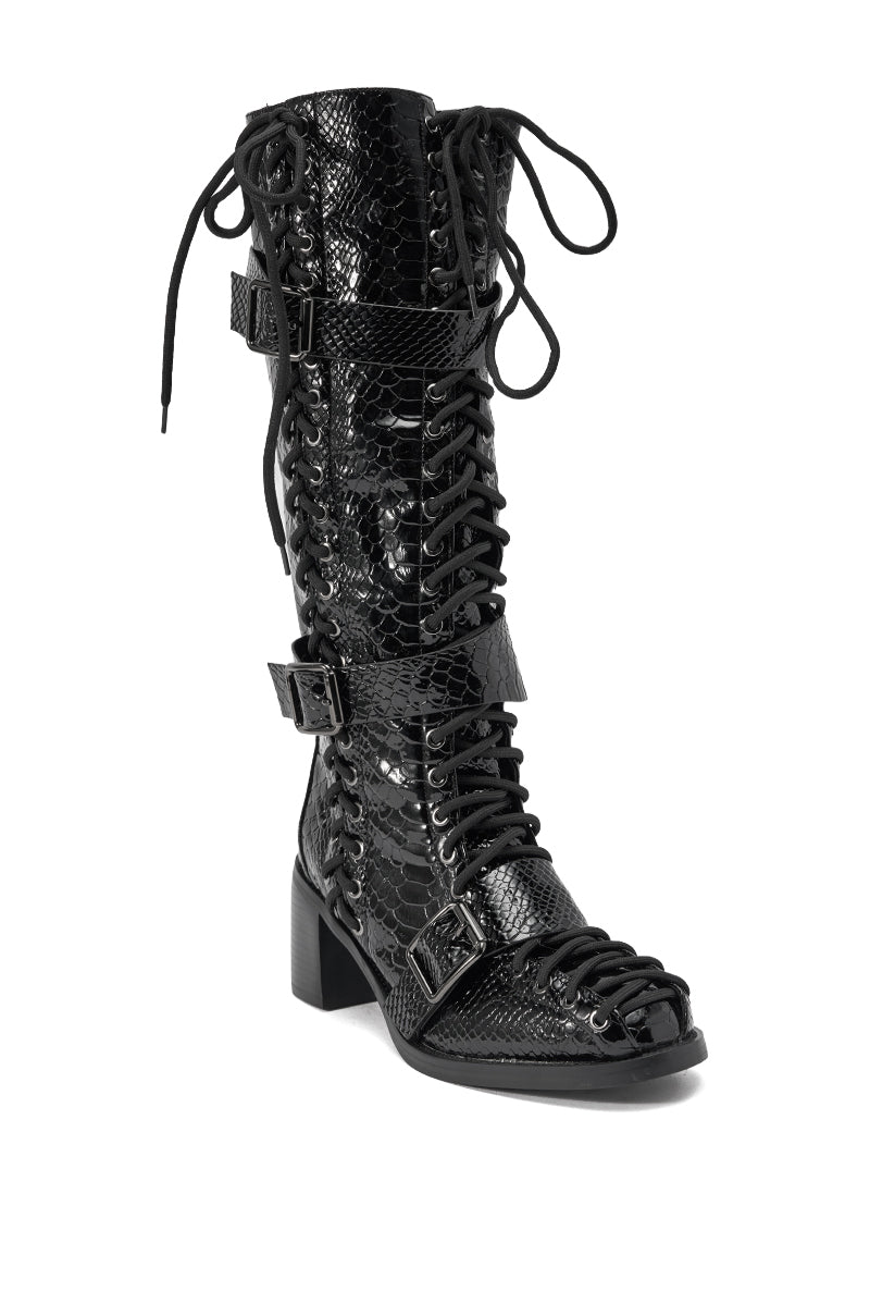 The AZALEA WANG MAKAR BLACK CROC LACE UP DETAIL BOOT is a black knee-high boot with a chunky heel, open toe, faux croc texture, cutout accents, lace-up front, and two buckle straps.