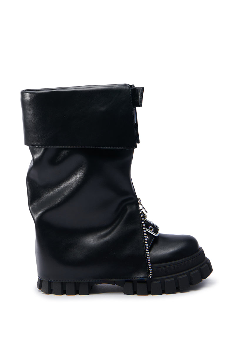 The AZALEA WANG MALEKO BLACK CHUNKY BOOT is crafted in faux leather and features a high, slouchy shaft and a thick, rugged treaded sole. It includes a zipper and a decorative strap around the ankle, showcasing a bold moto style design.