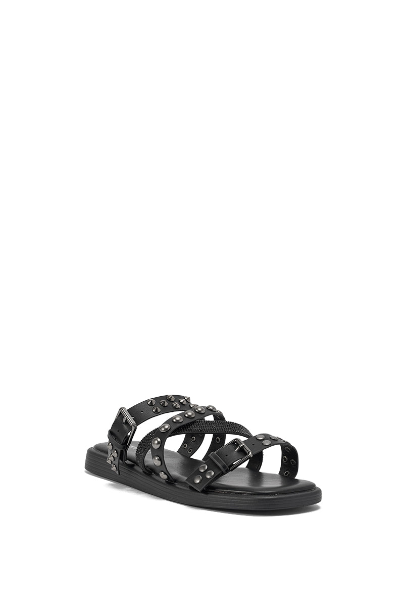 The AKIRA GOLD MANNING BLACK HARDWARE EMBELLISHED FLAT SANDAL features black crisscross straps with round silver studs and a side buckle, shown on a white background. 4