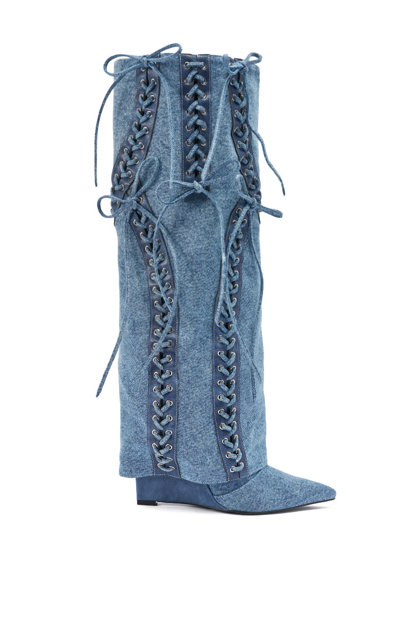 The AKIRA GOLD MANTIGNA DENIM WEDGE BOOT features tall, knee-high blue denim with pointed toe, wedge heel, decorative crisscross corset lacing on front and sides, tied bows, and textured fabric for extra style.
