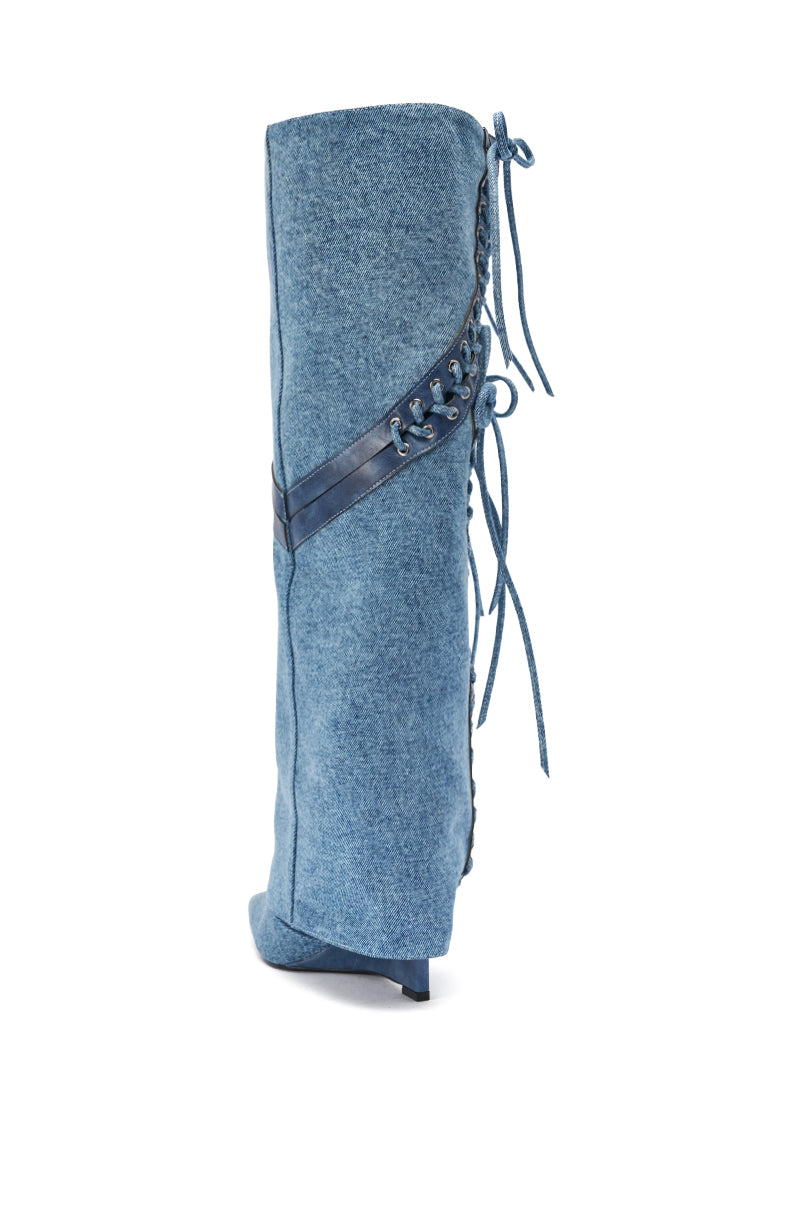 The AKIRA GOLD MANTIGNA DENIM WEDGE BOOT is a tall blue denim boot with corset lacing, a slim high heel, and a diagonal leather strap, shown against a plain white background.