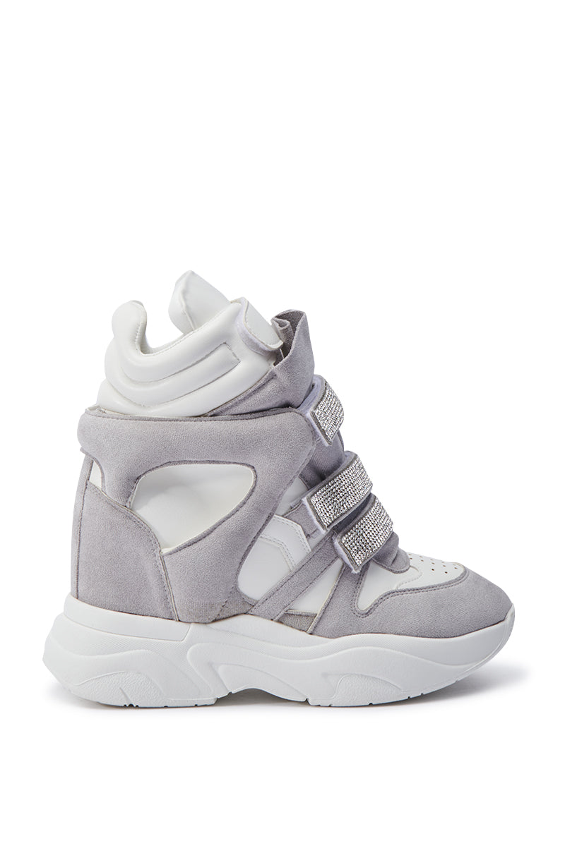 The MARANTO WHITE WEDGE SNEAKER is a fashionable high-top, featuring gray and white faux suede and leather accents. It boasts rhinestone-adorned velcro foot straps, a chunky white sole, and a cushioned ankle design for ultimate comfort and style.