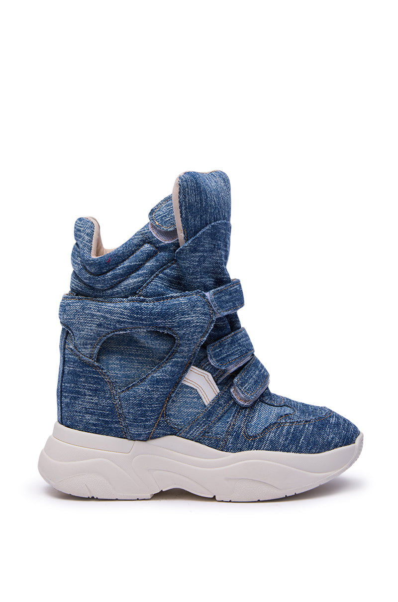 The MARANTO DENIM WEDGE SNEAKER features a blue denim-like fabric, padded collar, cut-out details, three velcro straps, and a thick white rubber sole. Shown in side view on a white background.