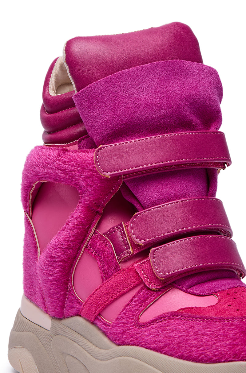 A close-up of the MARANTO FUCHSIA COLOR BLOCKED WEDGE SNEAKER, showcasing vibrant pink suede, leather, and faux fur textures with three Velcro straps, a chunky beige sole, and a hidden wedge heel for added height.