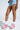 Against a light background, a person in frayed denim shorts showcases MARANTO CHUNKY PINK WEDGE HEEL SNEAKER with a color block design, paired with white ruffled socks.