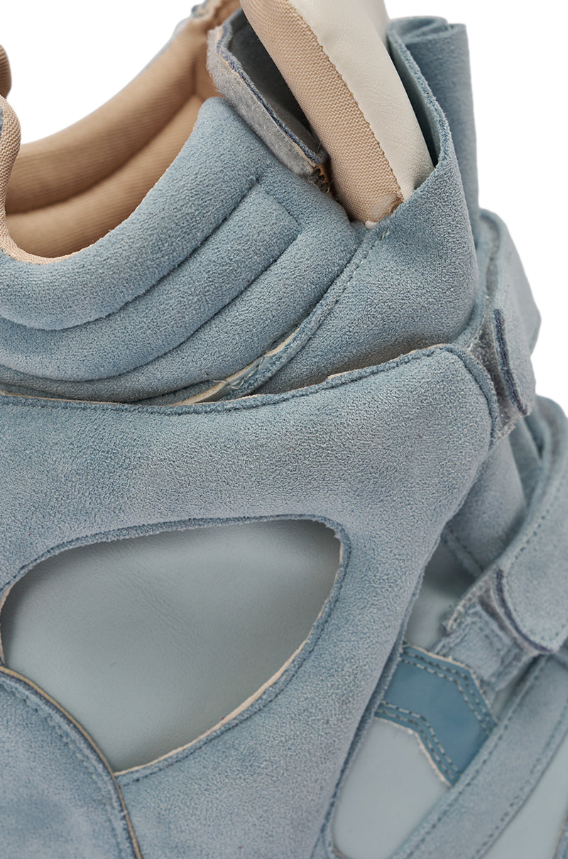 Close-up of the MARANTO BLUE WEDGE FAUX SUEDE SNEAKER: light blue, suede-like finish with detailed stitching, layered panels, cut-out accents, and a padded beige and white lining—ideal for elevating any streetwear ensemble. 7
