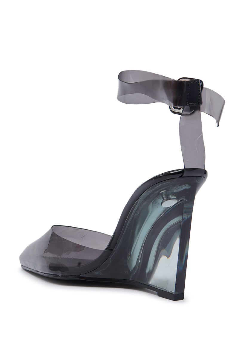The AZALEA WANG MARCO SMOKE PVC PUMP features a single high-heeled wedge, transparent smoky gray PVC design, matching ankle strap with buckle, glossy finish, sculpted silhouette, and pointed toe. 7