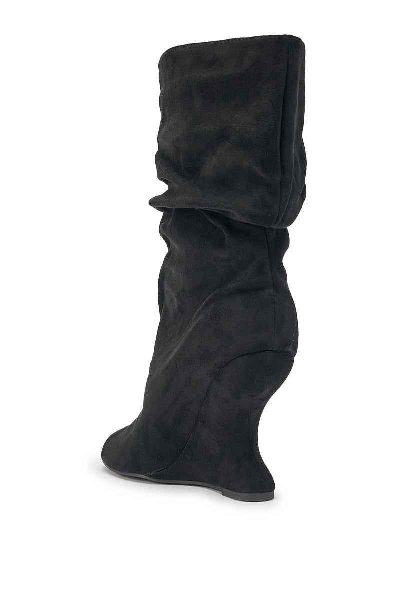 The AZALEA WANG MARIN BLACK FAUX SUEDE WEDGE BOOTIE features a slouchy, chic design with a unique curved wedge heel, shown solo against a white backdrop. 6