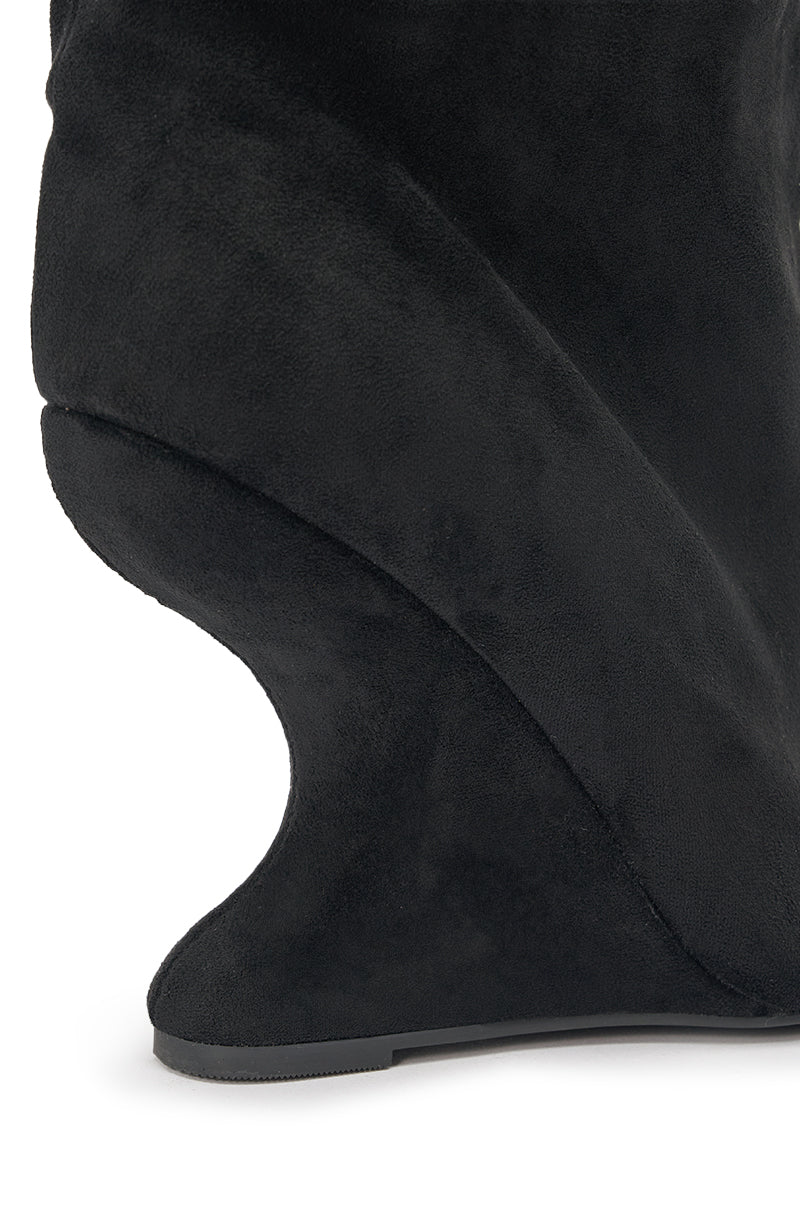 Close-up of the AZALEA WANG MARIN BLACK FAUX SUEDE WEDGE BOOTIE, featuring a smooth, curved design and an unusual sculptural wedge heel. The soft, velvety faux suede enhances its unique and modern silhouette. 7