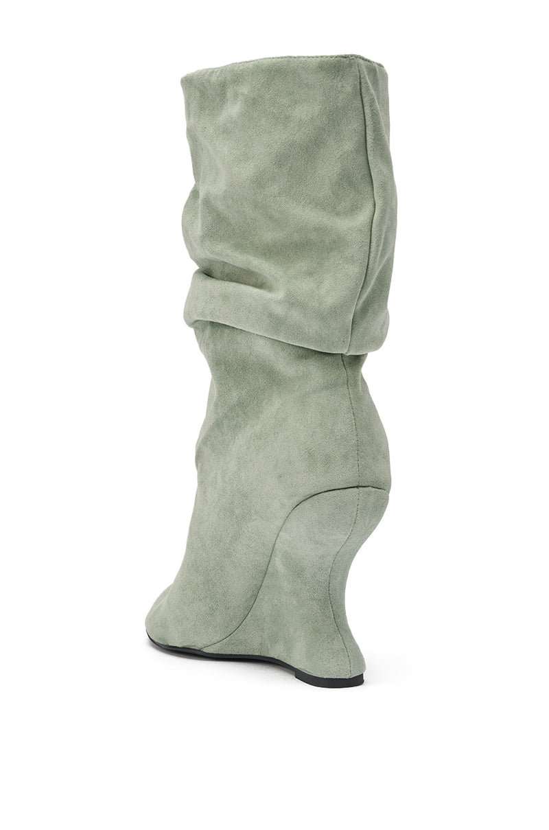 The AZALEA WANG MARIN SAGE FAUX SUEDE WEDGE BOOTIE features a sage green faux suede finish, a slouchy knee-high design, and a sculpted wedge heel, displayed from the back and side on a white background. 6