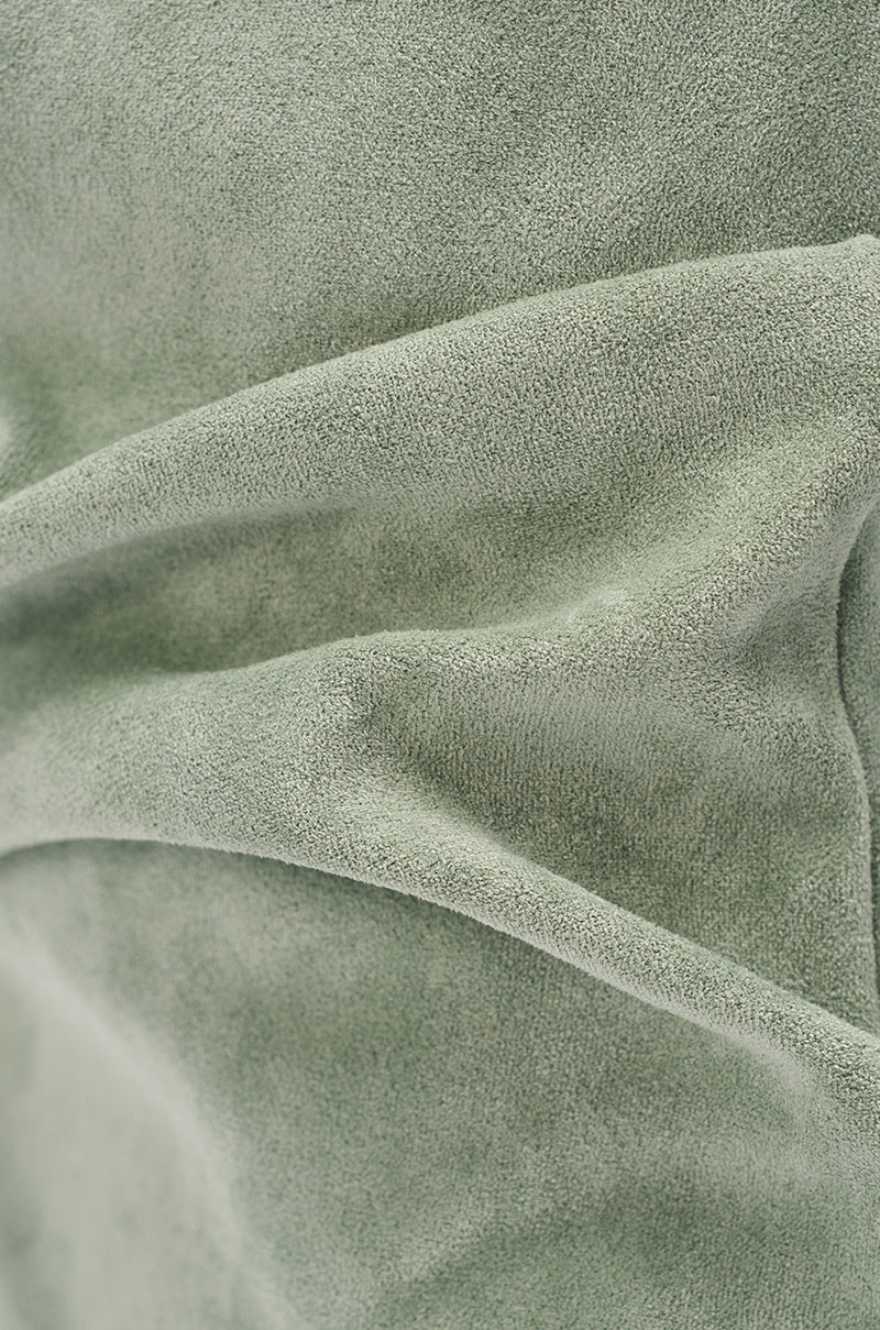 Close-up of the AZALEA WANG MARIN SAGE FAUX SUEDE WEDGE BOOTIE shows soft sage green faux suede with gentle folds and a velvety, textured surface—ideal for crafting stylish footwear. 7