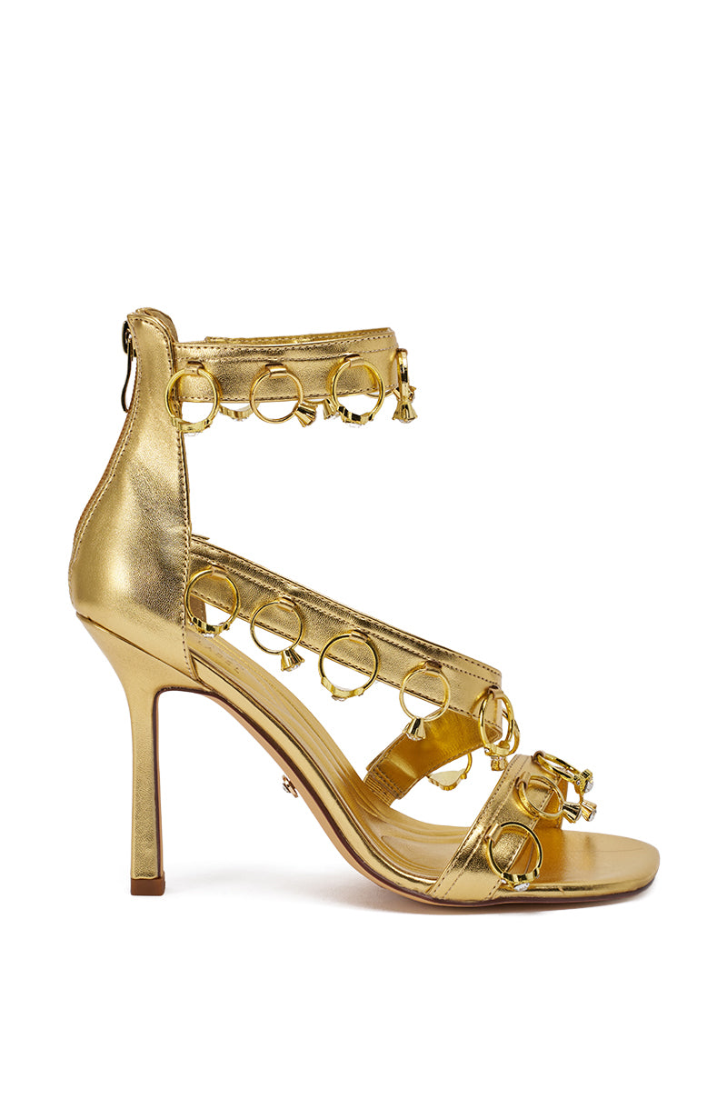 The AKIRA GOLD MARQUISE GOLD STILETO SANDAL WITH RINGS features two ankle straps and a toe strap adorned with circular metallic rings and small studs, a marquise stiletto heel, closed back, and rear zipper for an elegant finish. 6