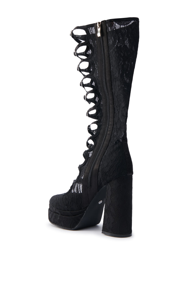 The AZALEA WANG MARRIGOLD BOOT IN BLACK LACE is a single knee-high boot featuring a chunky heel, platform sole, ornate semi-transparent lace design, side zipper, back cutout with mechanical eyelets and an almond toe for elegance.