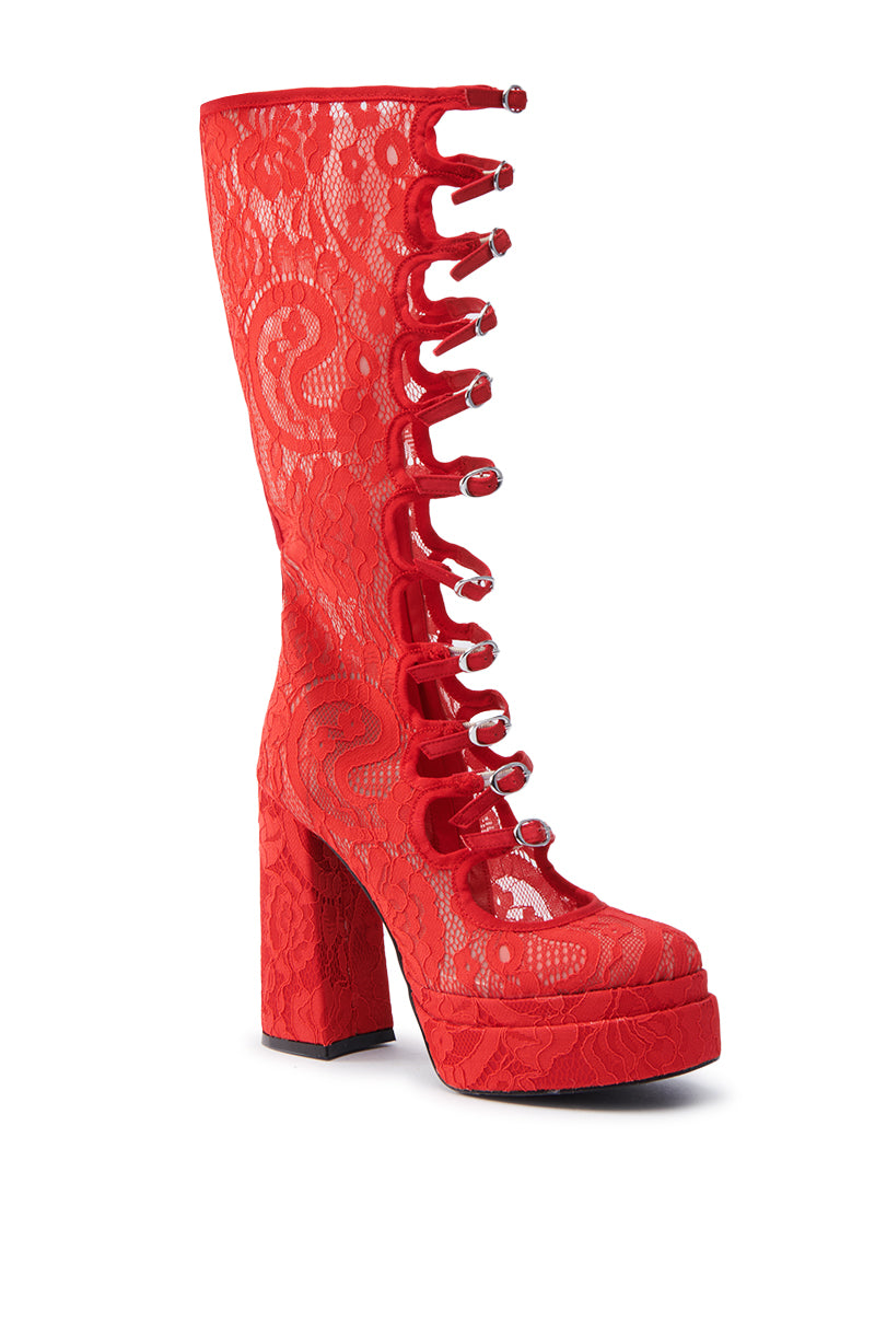 The AZALEA WANG MARRIGOLD BOOT IN RED LACE is a bold knee-high lace-up boot, featuring intricate floral lace patterns, metal eyelets, a unique cut-out front, tall chunky heel, and a platform sole for added height.