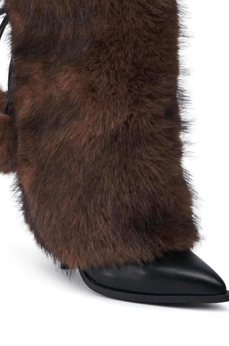 A close-up of the AZALEA WANG MAYRA BROWN BOOTIE features a high heel, black pointed toe, and a brown furry covering on the mid-calf shaft.