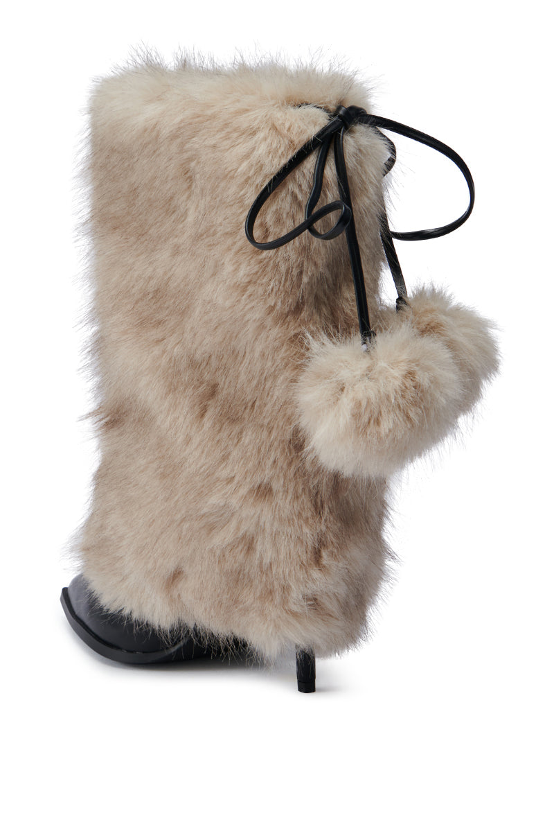 The AZALEA WANG MAYRA TAUPE BOOTIE is a stylish faux leather bootie adorned with light beige faux fur, featuring a sleek stiletto heel and a decorative black ribbon tied in a bow on the side, complete with fuzzy pom-poms. It offers a luxurious and cozy appearance with its elegant mid-calf shaft.