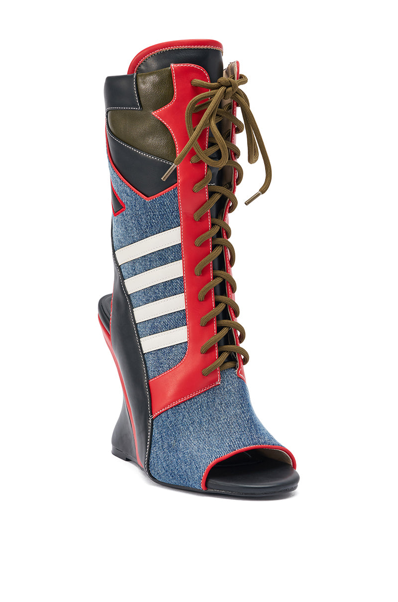 The AKIRA GOLD MAYWEATHER MULTI SPORTY LOOK WEDGE BOOTIE is a high-heeled, open-toe wedge with blue denim panels, red and black faux leather accents, white stripes, green tongue, and brown laces for a stylish sneaker-inspired look.