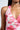 A close-up of a woman wearing the sleeveless, deep V-neck VIOLETS FOR ROSES PRINTED MAXI DRESS, featuring a pink and white botanical floral pattern, styled with a sparkling rhinestone choker and her long dark hair over her shoulder.