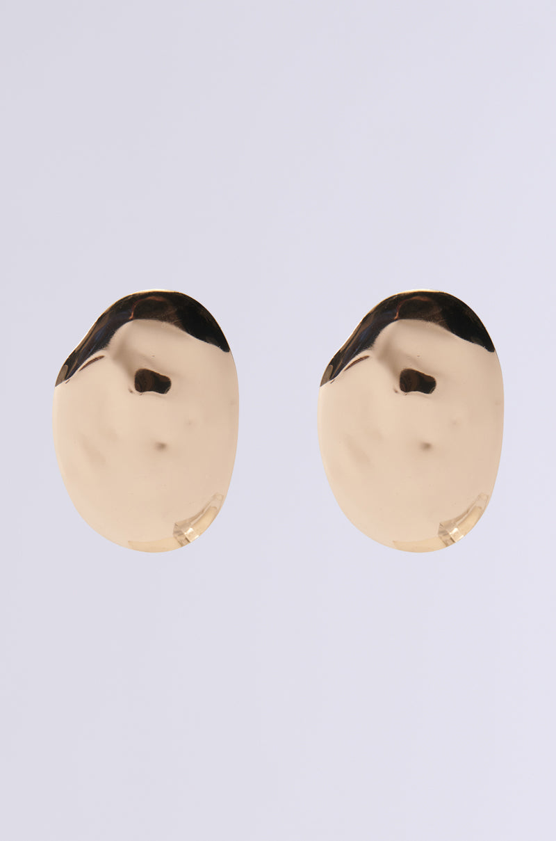 The DIDI STATEMENT EARRING features shiny, gold-toned oval shapes with smooth, slightly uneven hammered surfaces set against a light gray background.