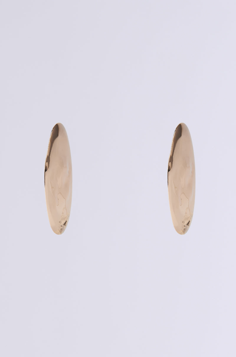 The DIDI STATEMENT EARRING features two oval gold earrings with a smooth, reflective surface displayed on a white background. Their minimal design highlights a glossy finish and elegance, with subtle hammered detailing adding a unique touch to these statement pieces.