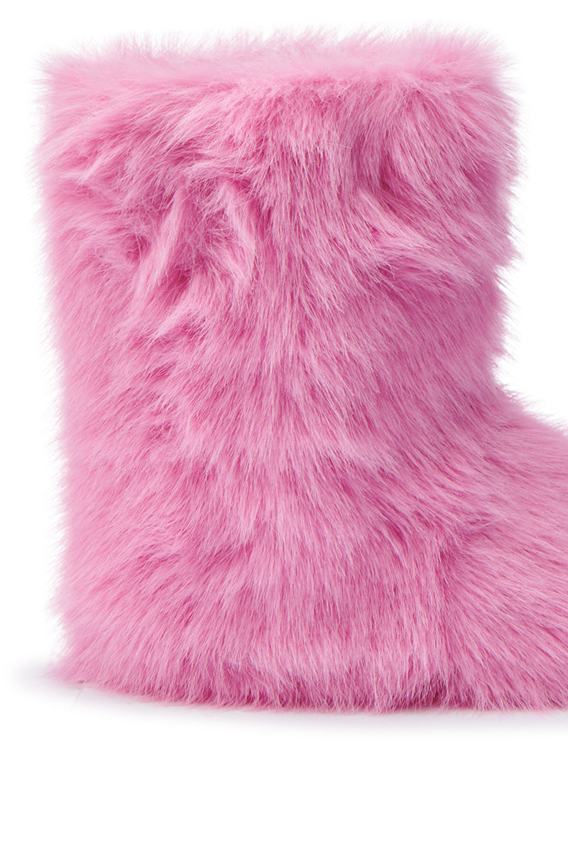 A close-up of the MELANIE PINK FURRY BOOTIE reveals its bright pink, textured faux fur surface. This cozy sherpa boot features a soft, plush appearance that covers the ankle area against a plain white background. 6