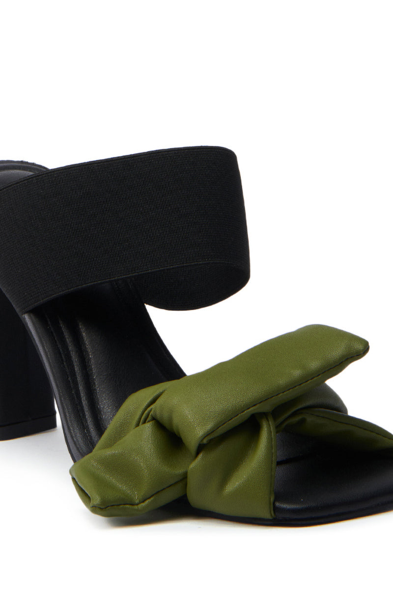 The AZALEA WANG MENES BLACK PUFF DETAIL SANDAL is a stylish women's sandal with a chunky black heel, wide ankle strap, olive green knotted puff detail strap over the toes, and a black footbed with slight cushioning.