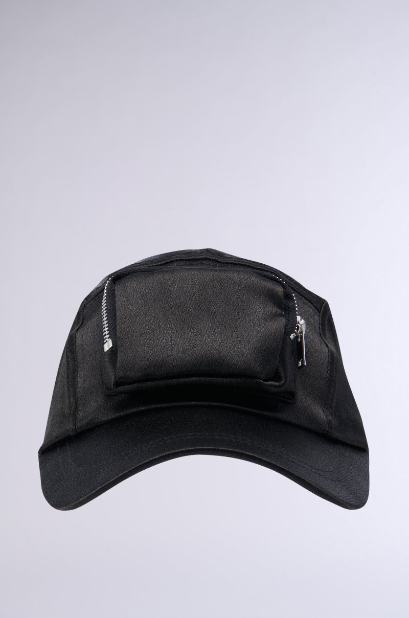 The SATIN LUXURY CARGO SNAPBACK in black boasts a slightly curved brim and a small zipper pocket on the front panel, located above the brim. The pocket is equipped with a silver zipper and pull tab. An adjustable velcro strap at the back ensures a perfect fit. The cap is showcased against a solid light gray background. 1