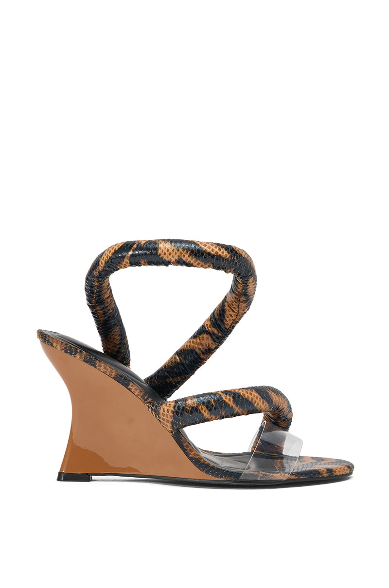 The AKIRA MINORU BROWN ANIMAL PRINT WEDGE SANDAL is a women's Y2K-inspired wedge featuring tan and black animal-print straps, a clear toe strap, and a glossy tan wedge heel. 2