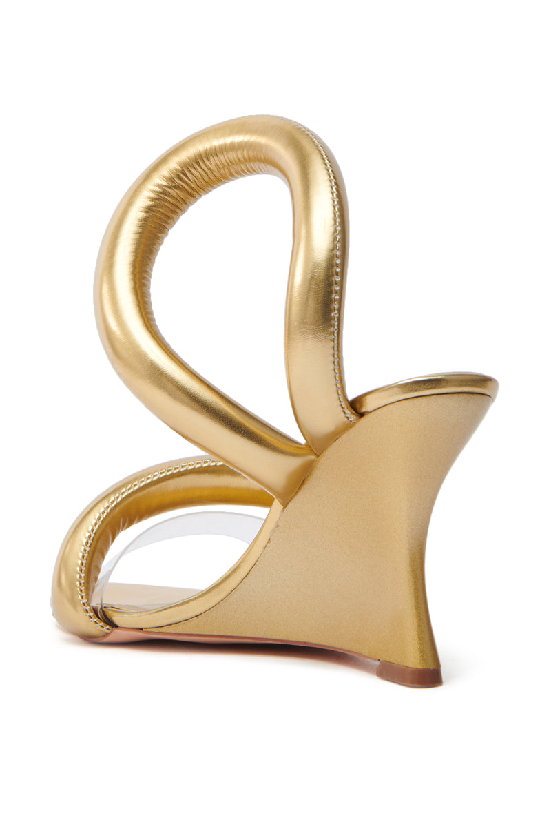 The AKIRA MINORU GOLD WEDGE SANDAL features a unique sculptural design with an open almond toe, curved loop-like heel structures in metallic faux leather, and a subtle front platform for an abstract artistic touch.