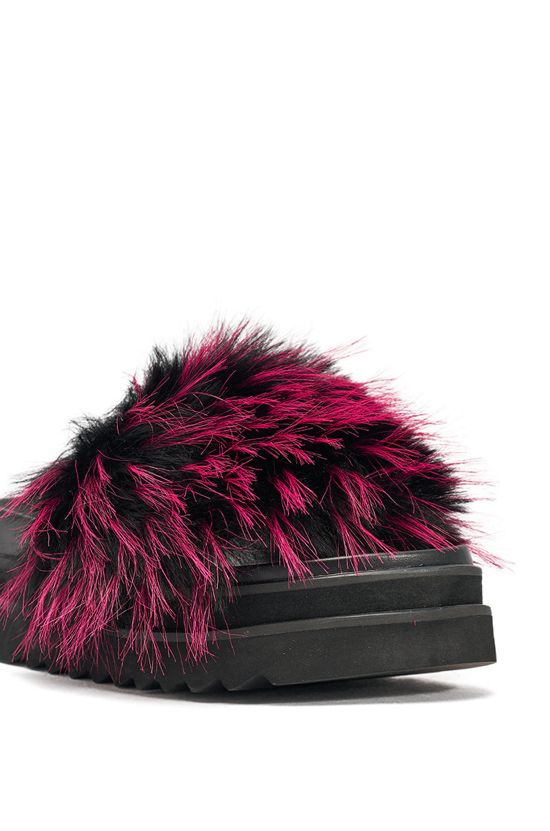 A close-up of the AKIRA MIRAY PINK MULTI FUR SLIDE, a black faux leather platform slide with a fluffy black and bright pink faux fur strap, set against a white background. 7