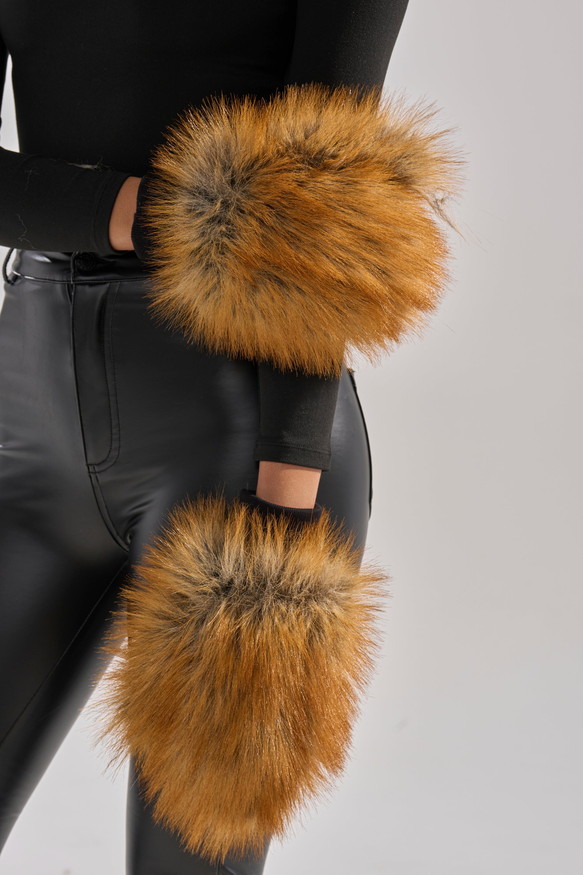 Wearing REALLY LIKE THAT FAUX FUR MITTENS—large, plush faux fur mittens that stand out against a black outfit and light background—is an eye-catching addition to any winter wardrobe. 2